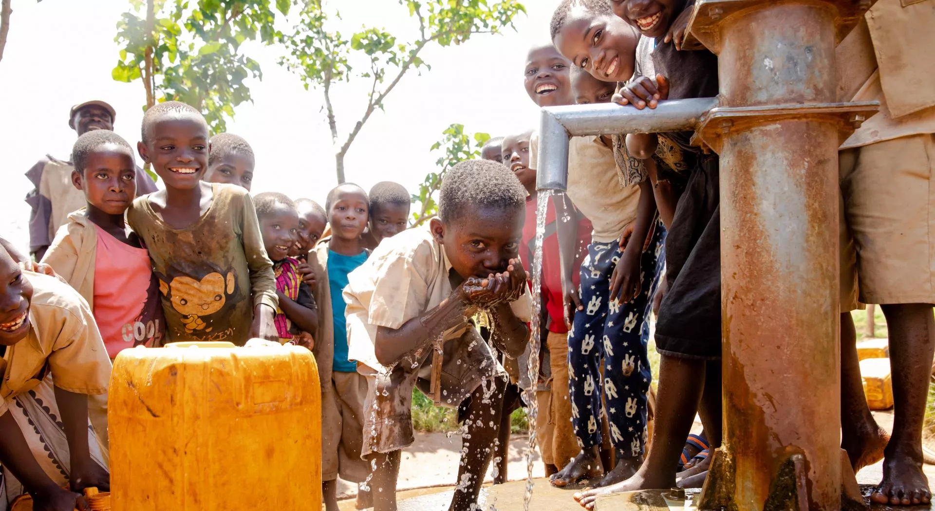 Een kind drinkt water uit de pomp