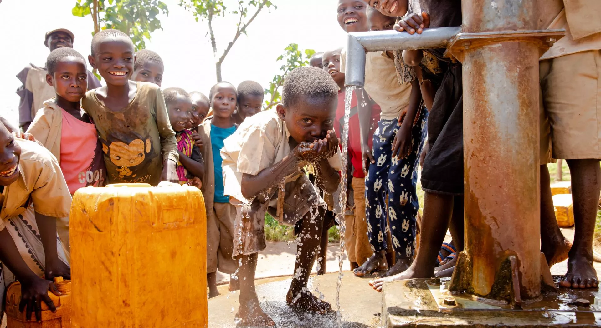 Een kind drinkt water uit de pomp
