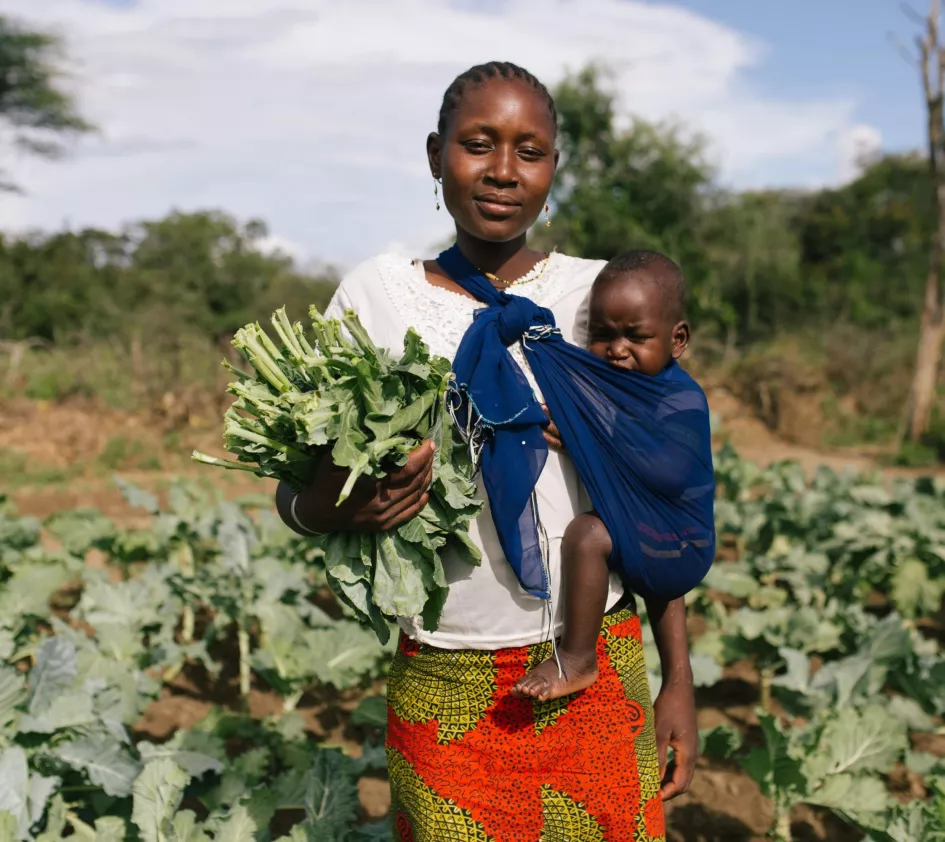 Vrouw in Afrika werkt op het land met kind in draagdoek