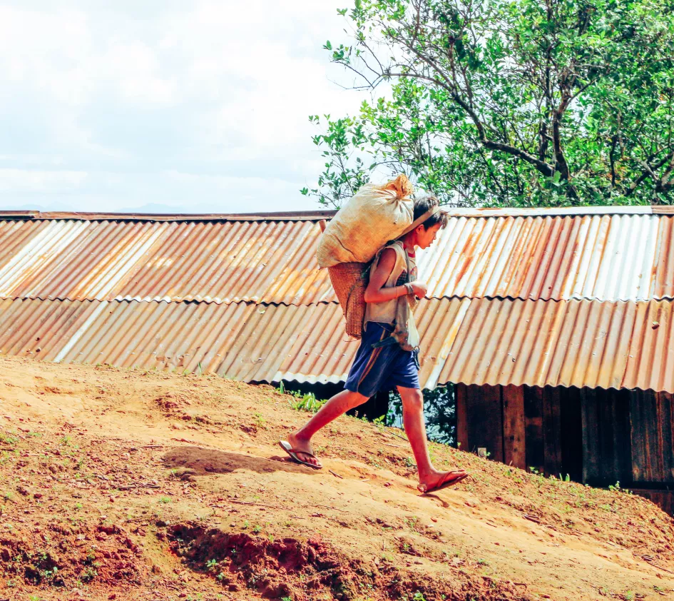 Jongen loopt met zware bepakking in Myanmar