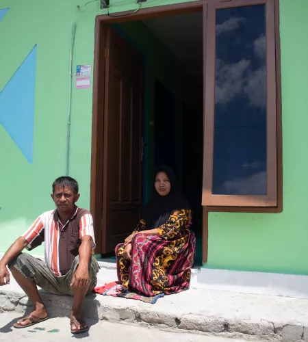 Tasrudin en zijn vrouw bij hun nieuwe huis, die hij zelf heeft gebouwd met hulp van ZOA, in 2020.