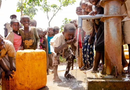 Een jongetje geniet van schoon drinkwater in Burundi