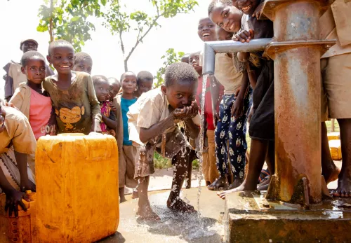 Een jongetje geniet van schoon drinkwater in Burundi