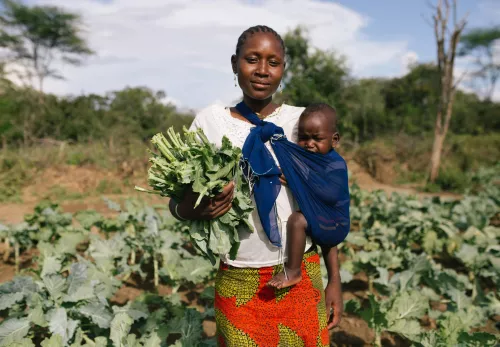 Vrouw in Afrika werkt op het land met kind in draagdoek