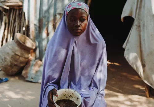 Habiba laat zien wat ze nog aan eten heeft voor de aankomende dagen met haar vier kinderen. In het pannetje zit een handjevol gestampt graan.